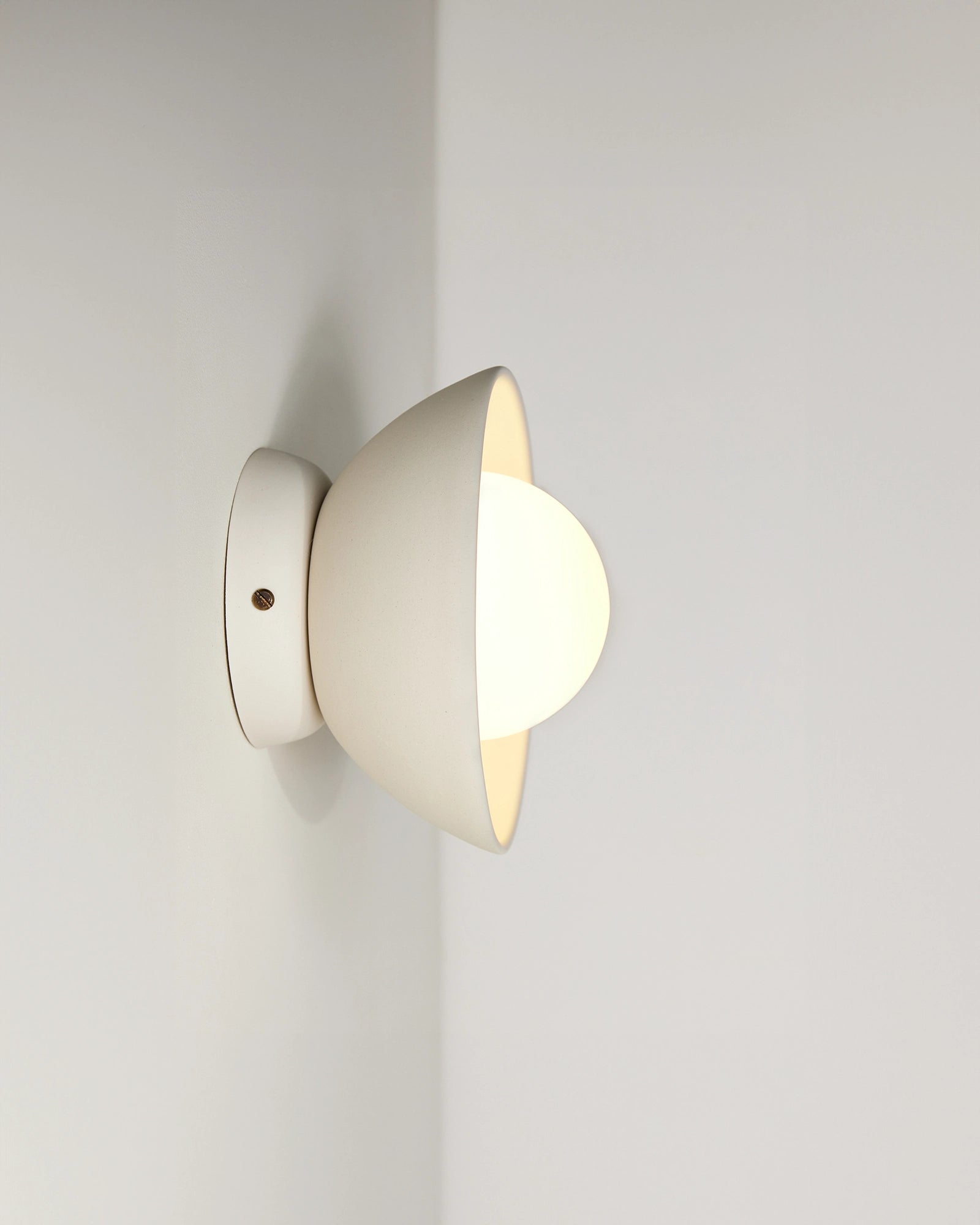Ceramic wall light fixture with orb light glass on a plain white background