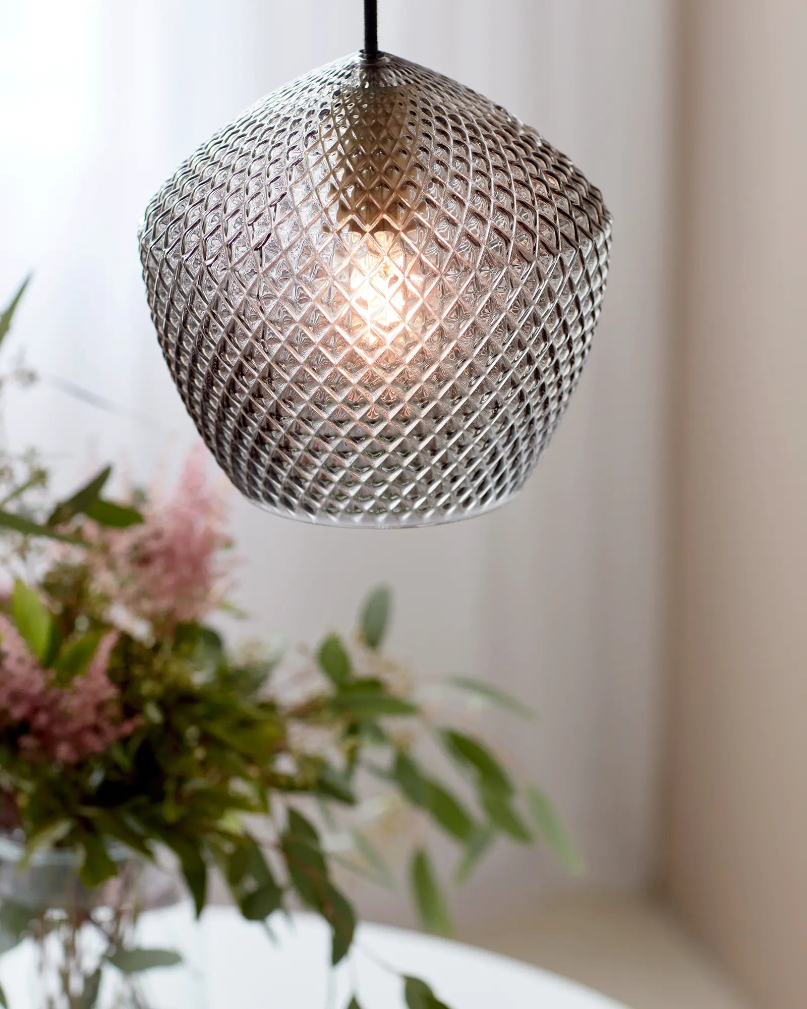 Orbiform glass pendant light above a table