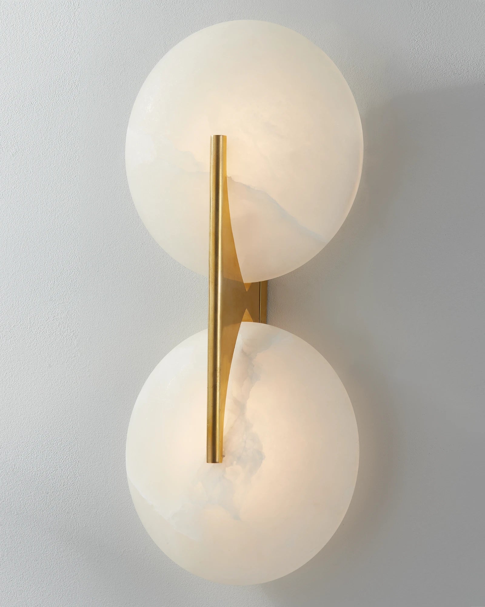 Wall-mounted light fixture with two spherical glass shades and a gold accent bar on a plain background.