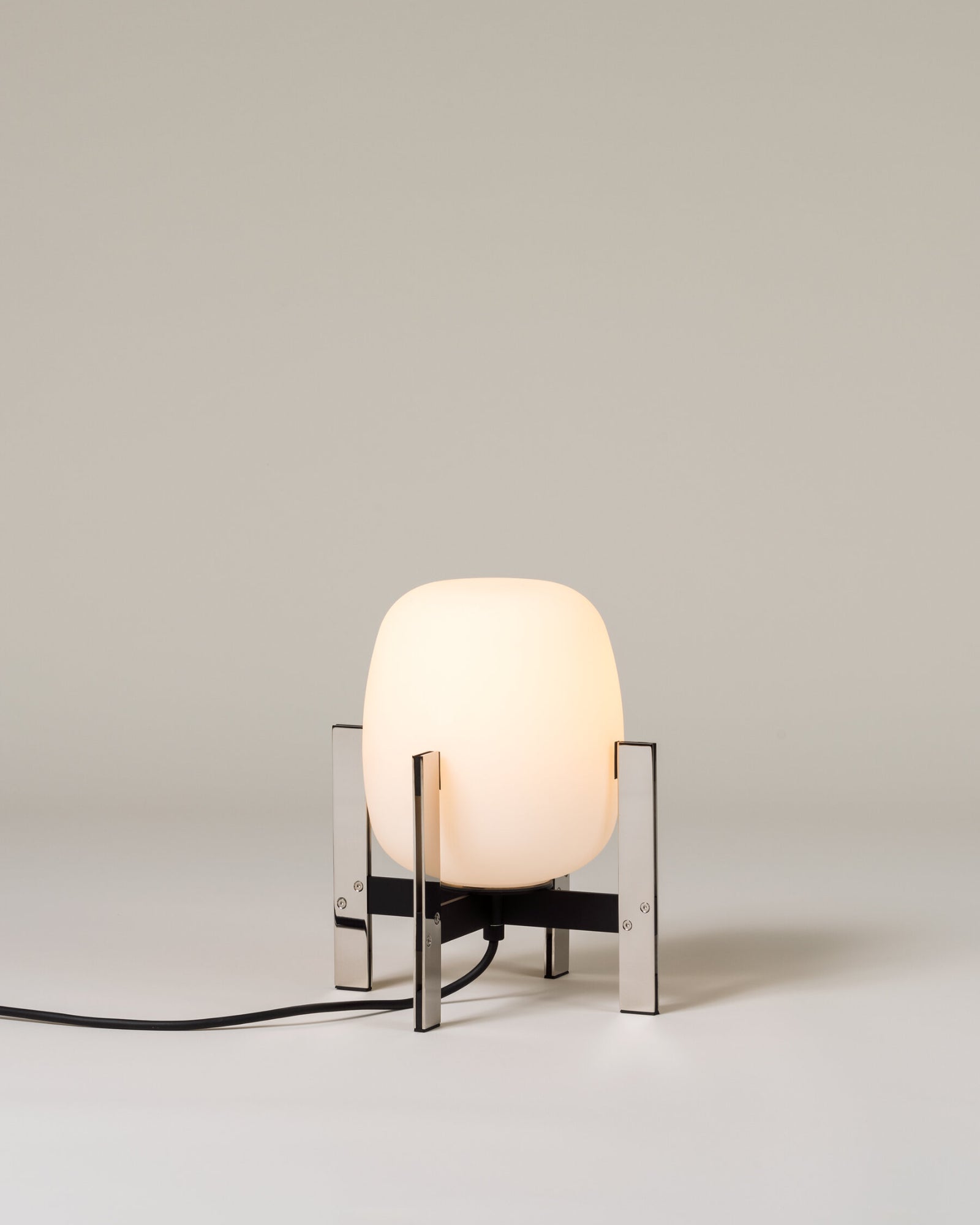 Contemporary table lamp called the Cestita Metallic Table Lamp in chrome metal finish by Santa & Cole featured in a living room.