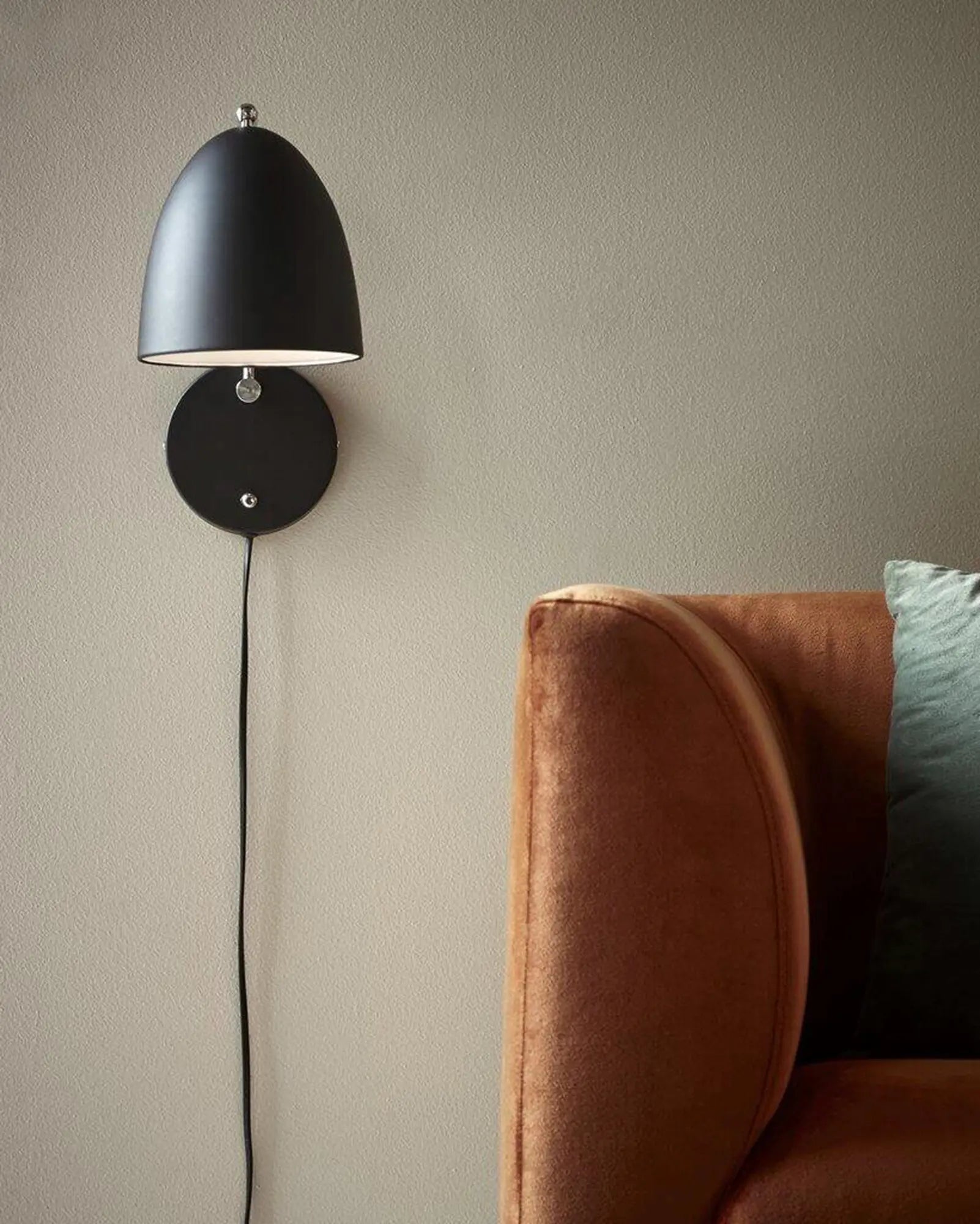 Alexander Wall Light Scandinavian minimalistic dome in black on the side of a sofa bed