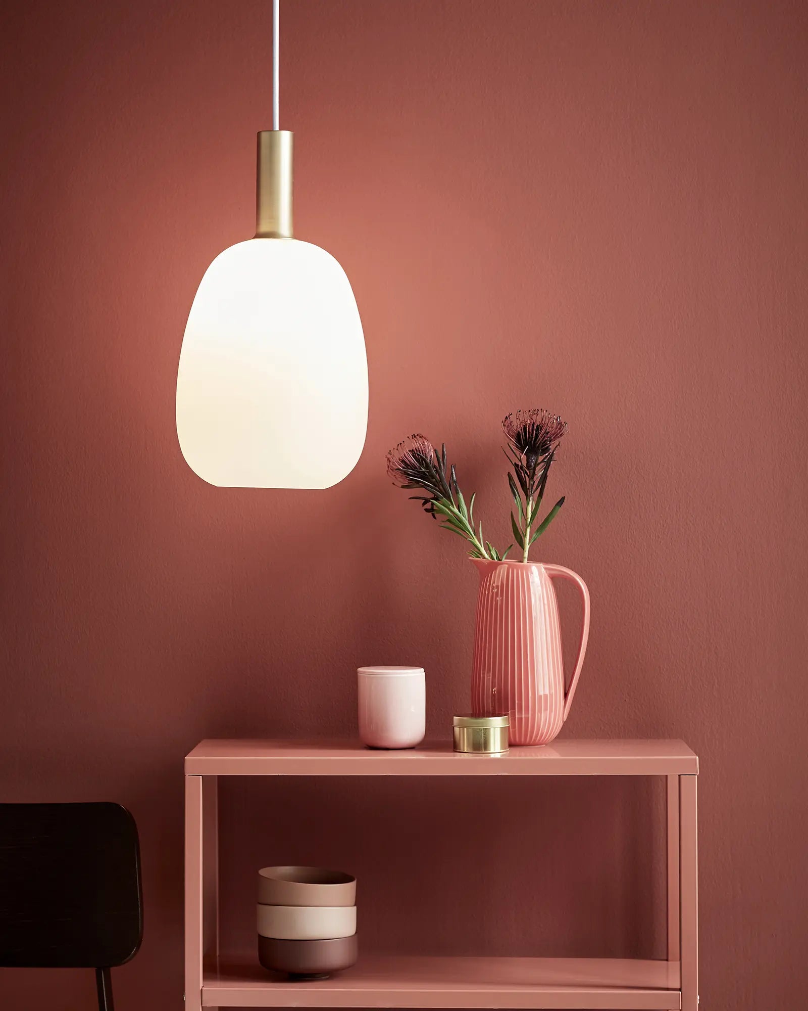 Alton Scandinavian Pendant light in blown glass opal and brass above a shelf unit