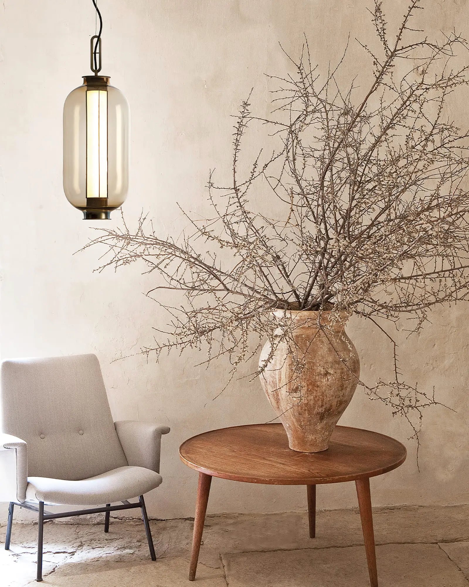 Bai Ba Ba tall bronze and blown glass Chinese lantern style pendant light on a chair in a lounge area
