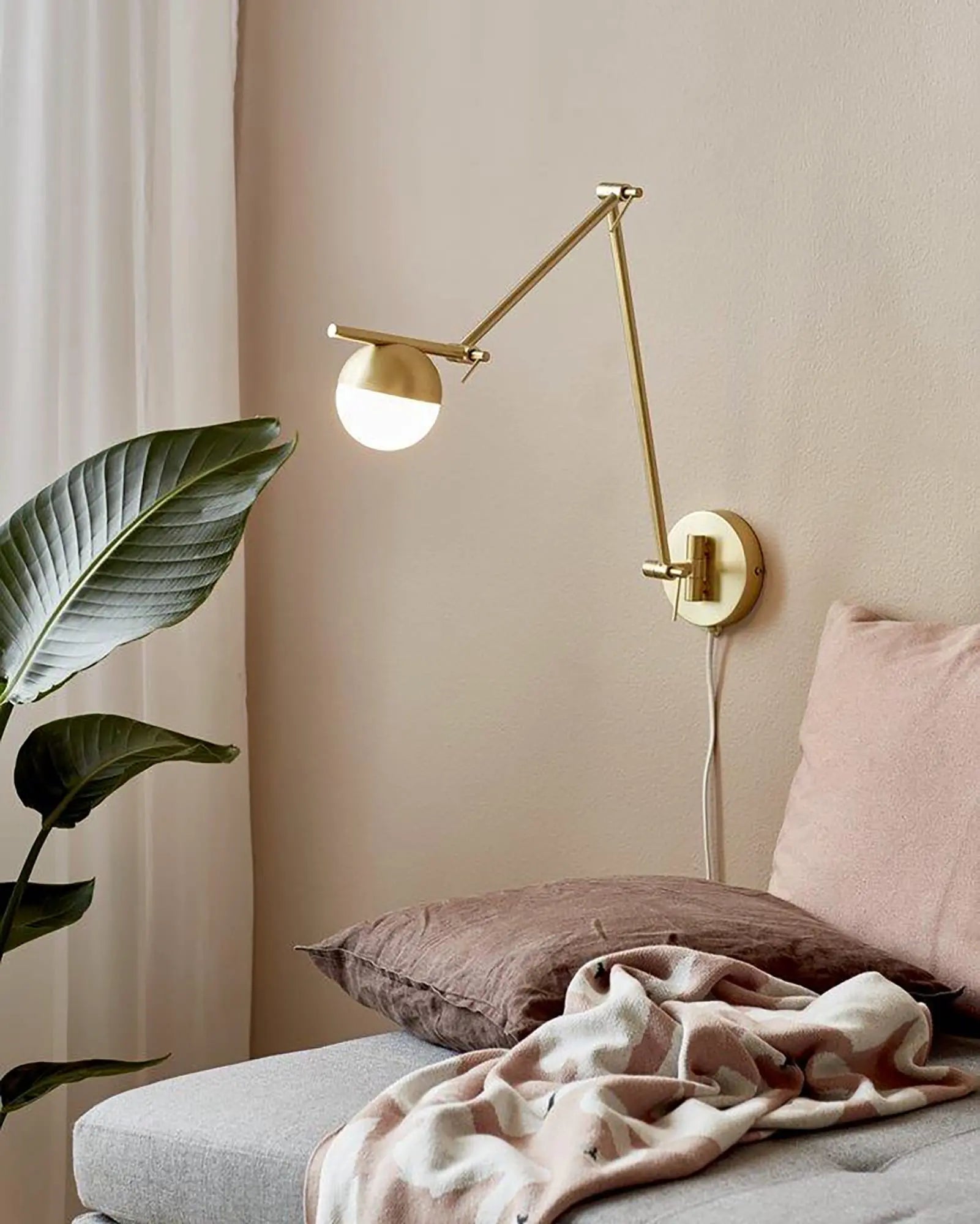 Contina adjustable minimal orb wall light on the side of a sofa