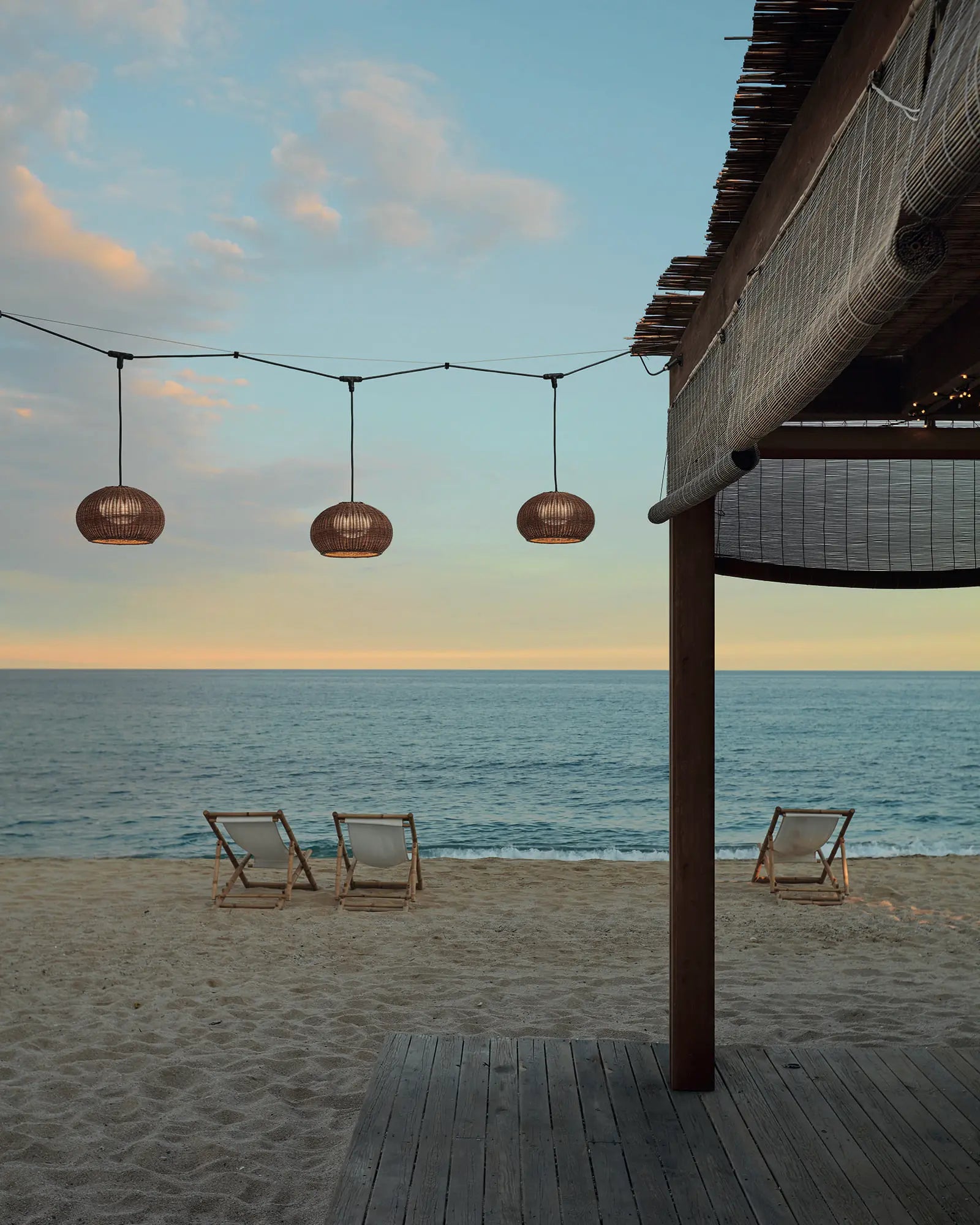 Garota woven contemporary coastal pendant light on a beach deck