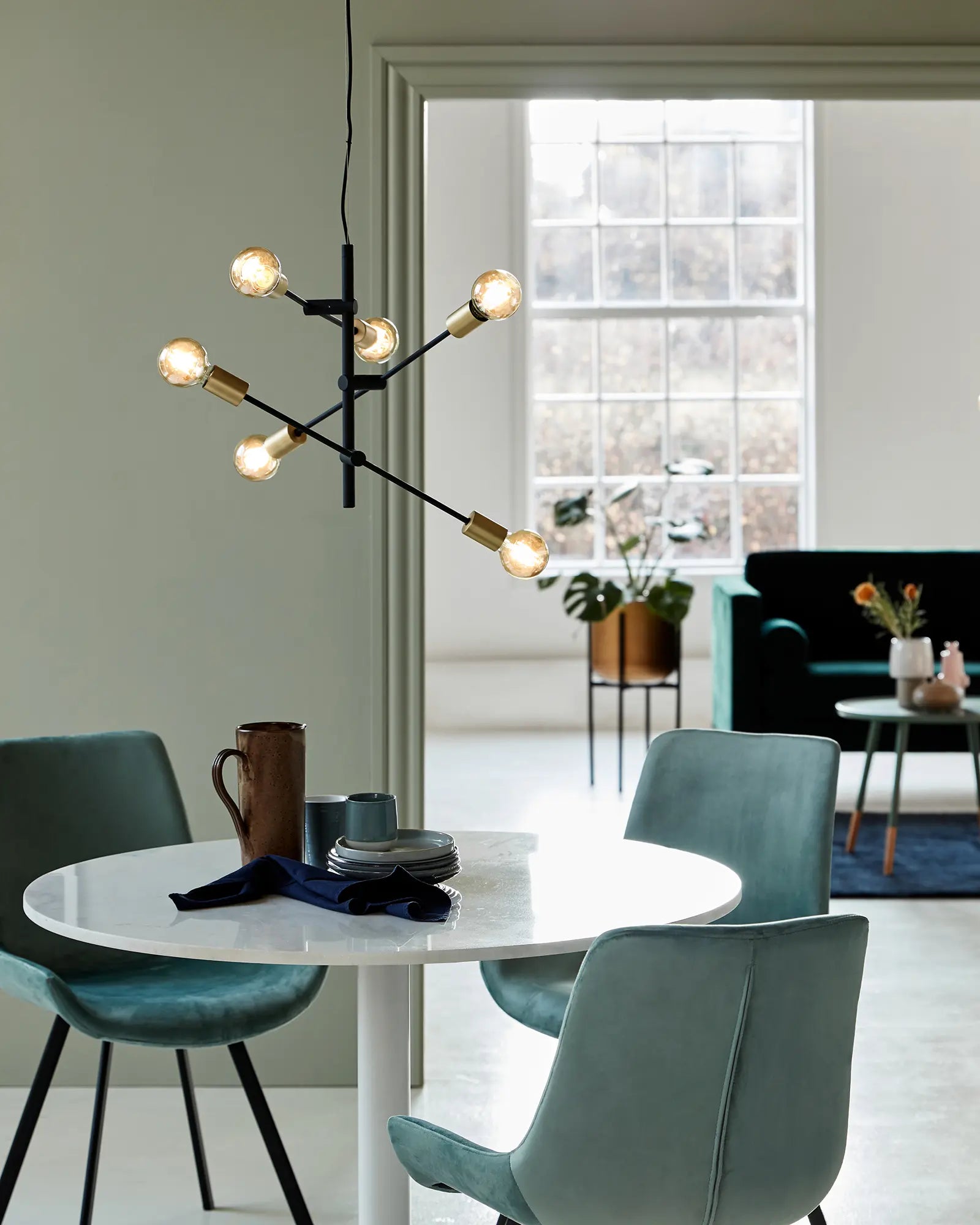 Josefine pendant light in black and brass vertival above a round table