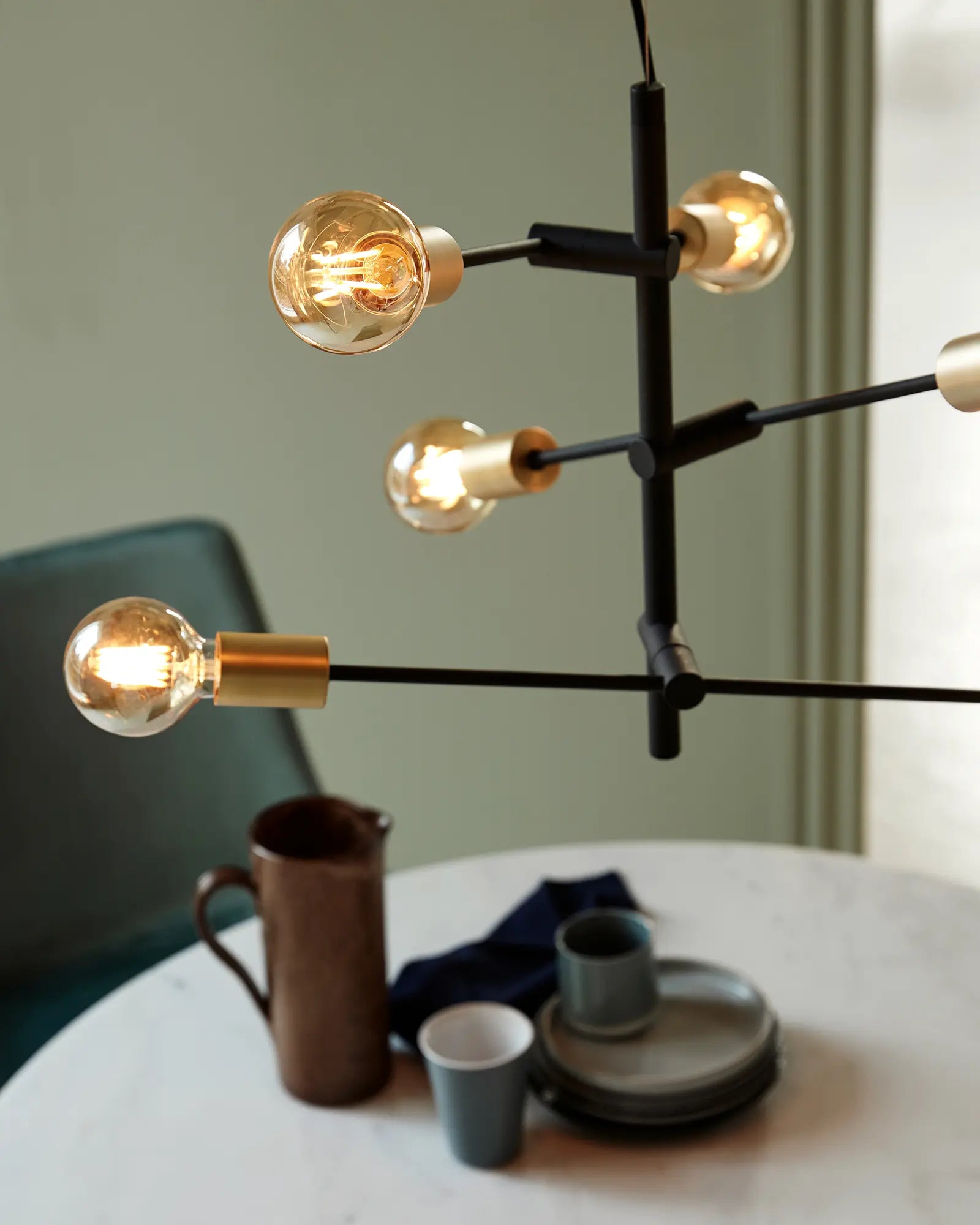 Josefine pendant light in black and brass  vertical above a coffee table detail