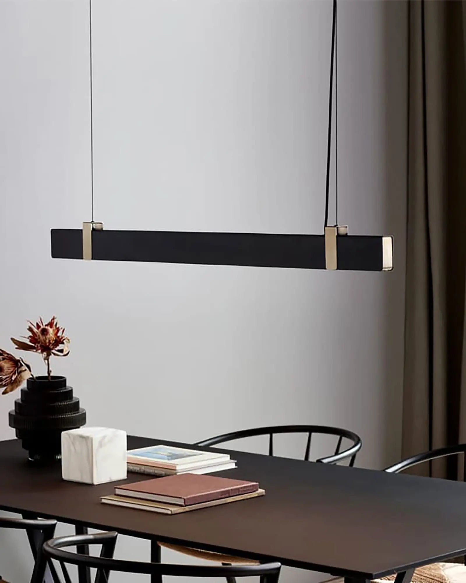 Lilt Scandinavian contemporary linear pendant light in black and brass above dining table