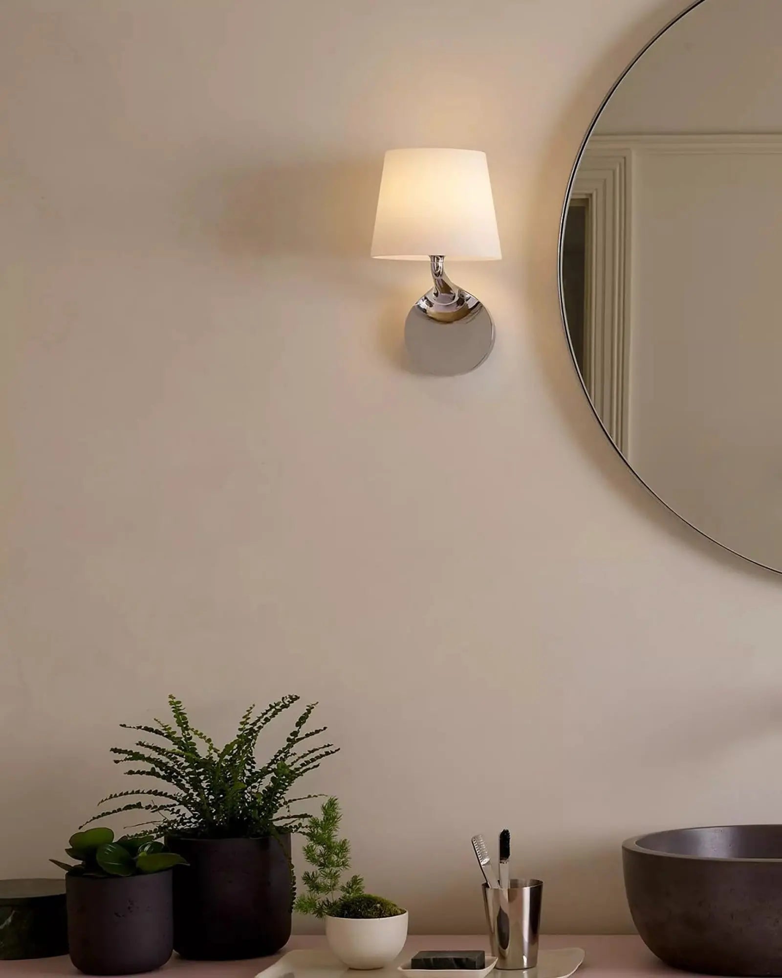Millie contemporary curvy bathroom wall light with metal body and glass shade on the mirror's side
