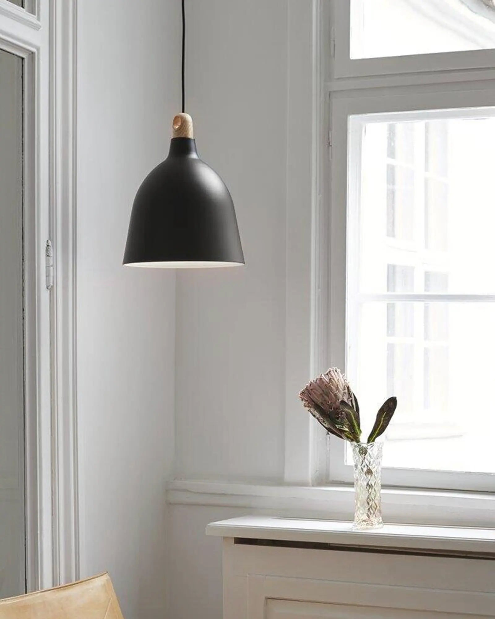 Moku Scandinavian contemporary timber and metal pendant light above a chair in a living area