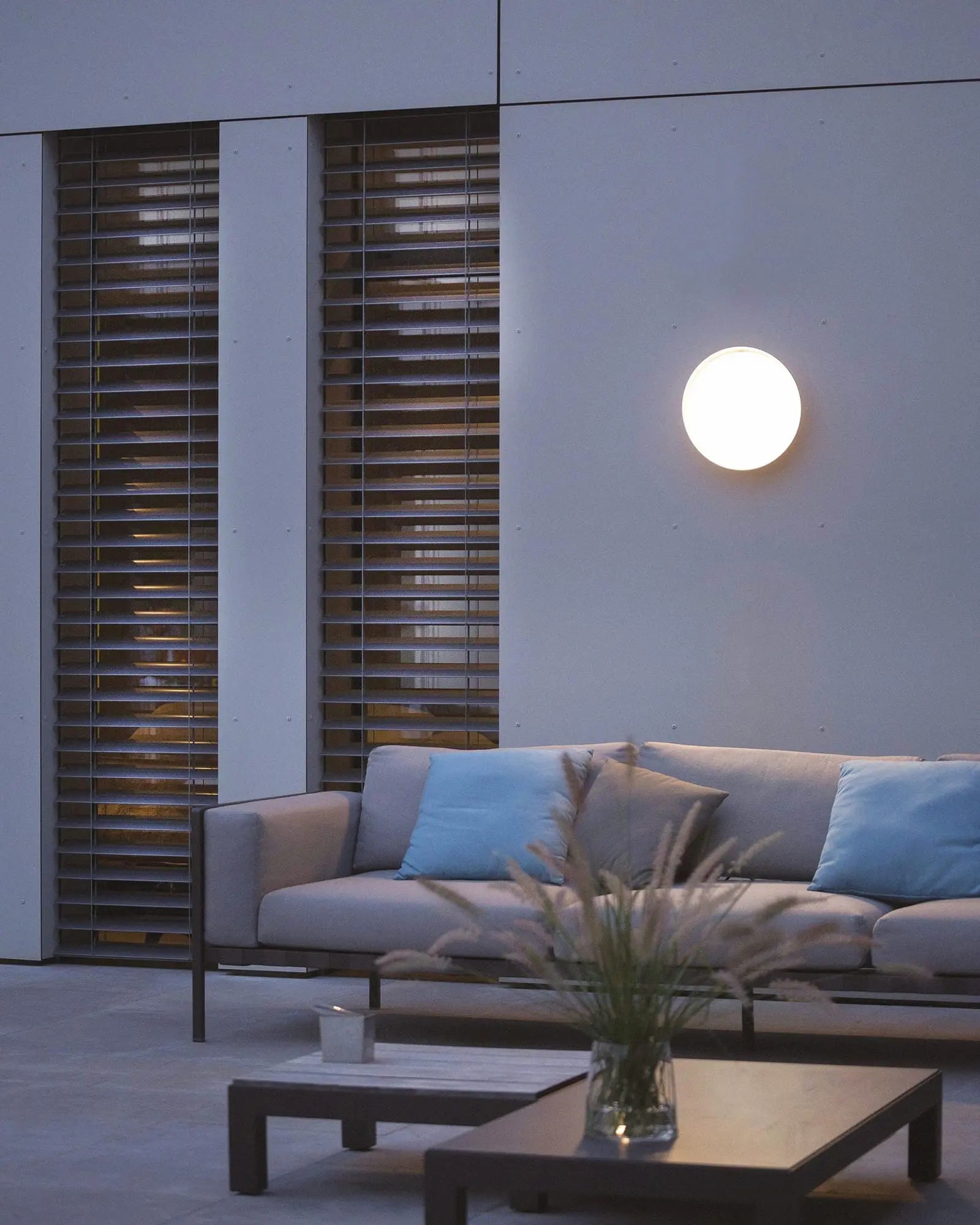 Mona Outdoor circular wall light above an outdoor lounge area