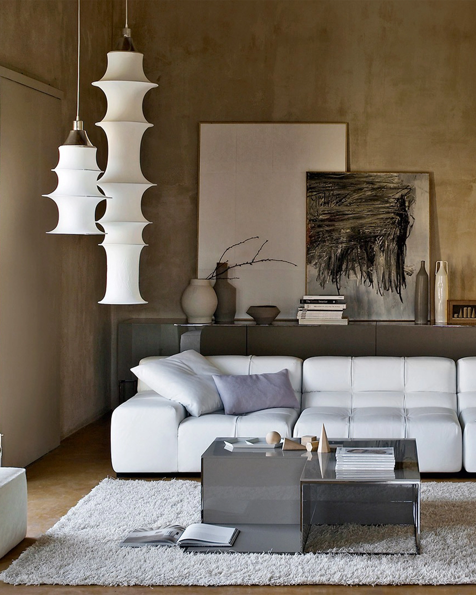 Modern living room with white sofa, coffee table, decorative items and the Falkland Pendant Light by Artemide.