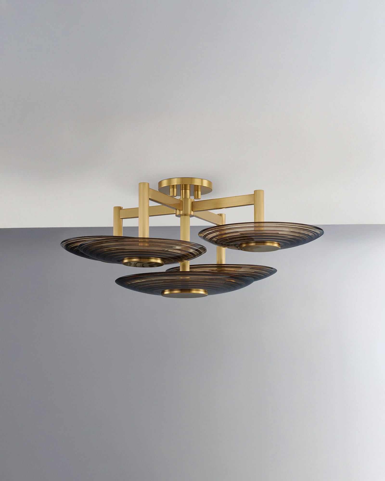 Modern ceiling light fixture with gold and amber glass design on a grey background