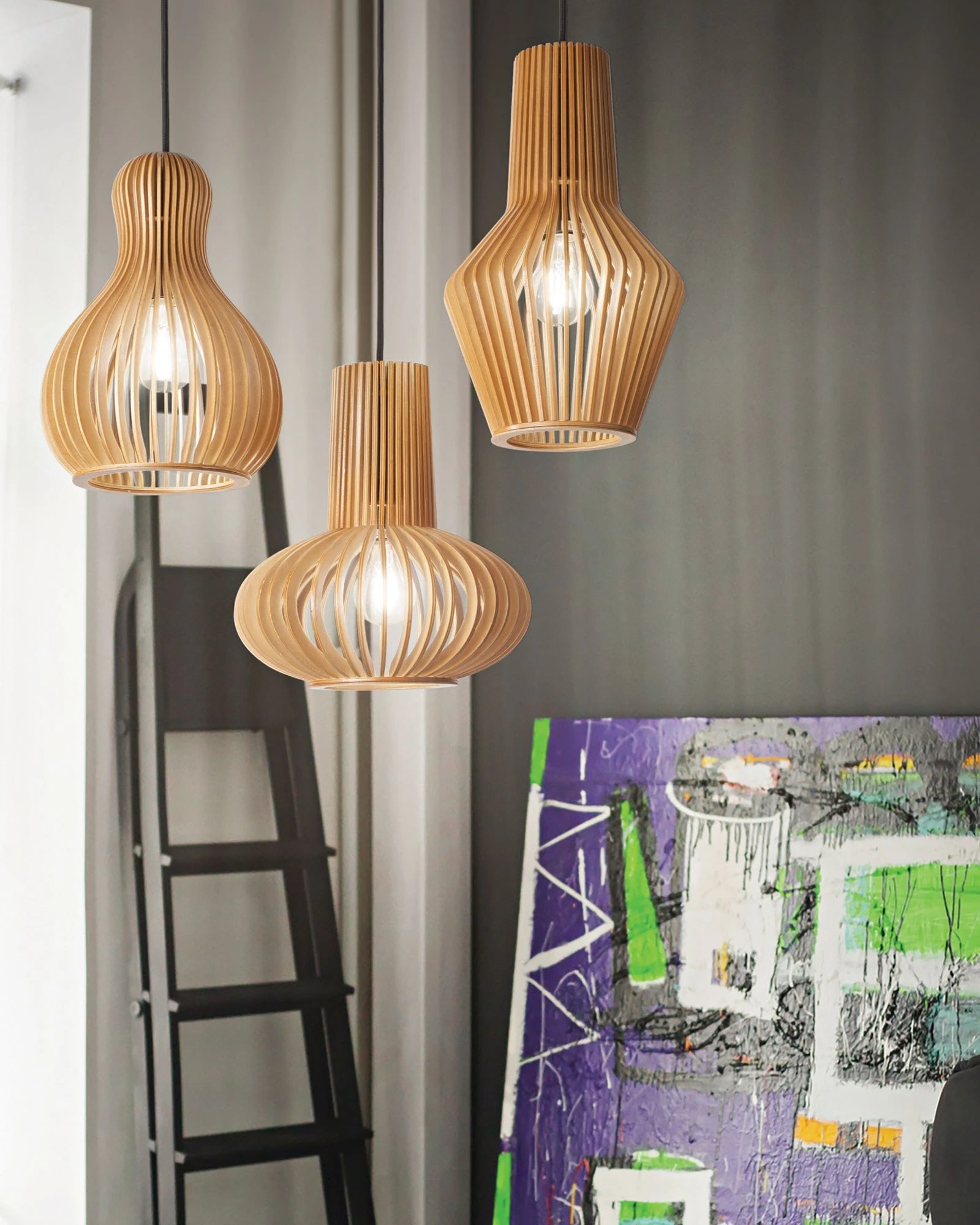Three wooden pendant lights hanging in a room with a ladder and colorful artwork.