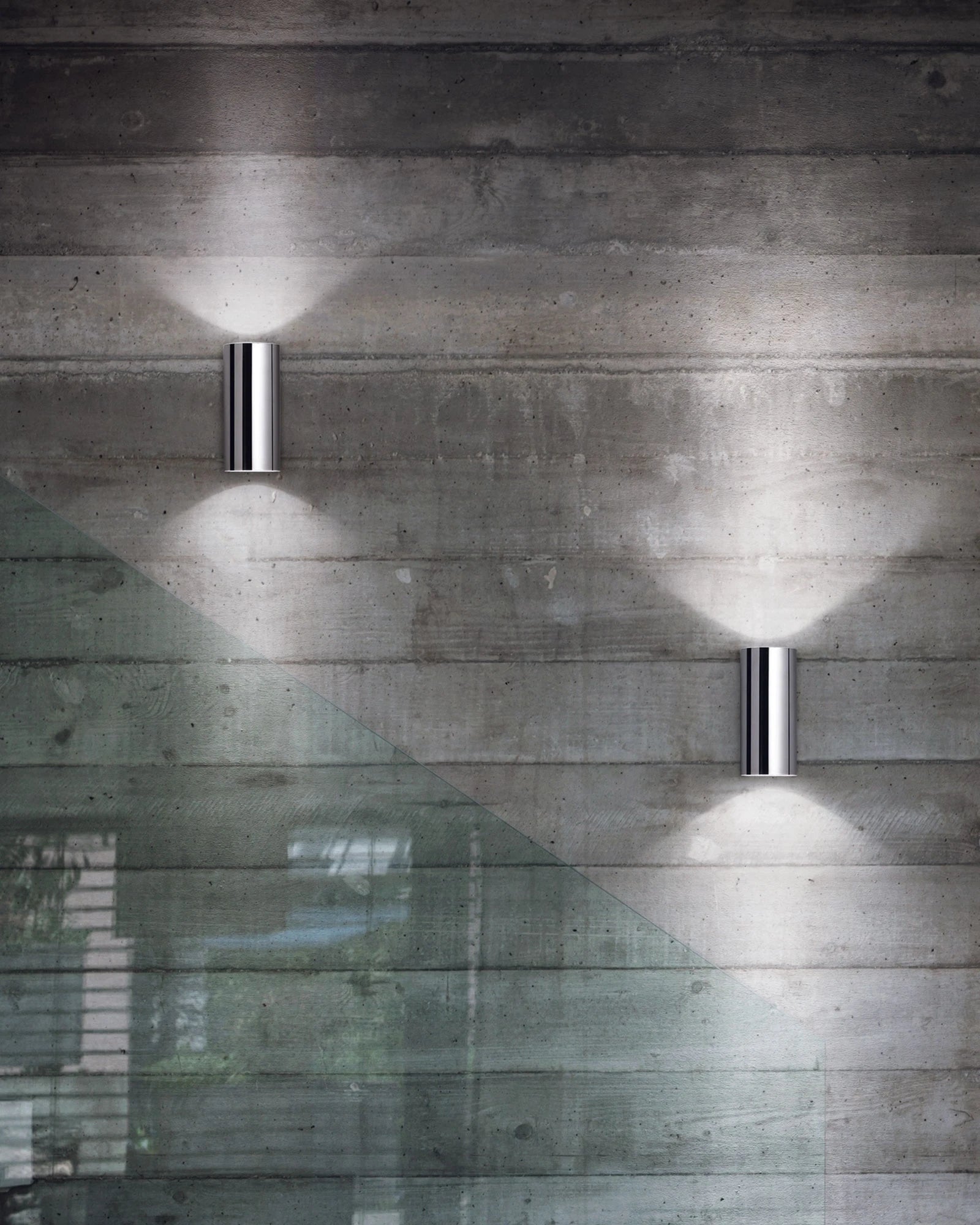 Two wall-mounted lights casting shadows on a concrete wall
