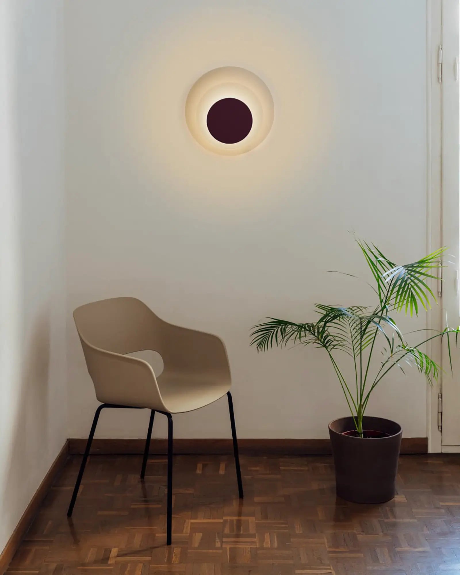 Elisa wall light in a living area above a chair and a plant