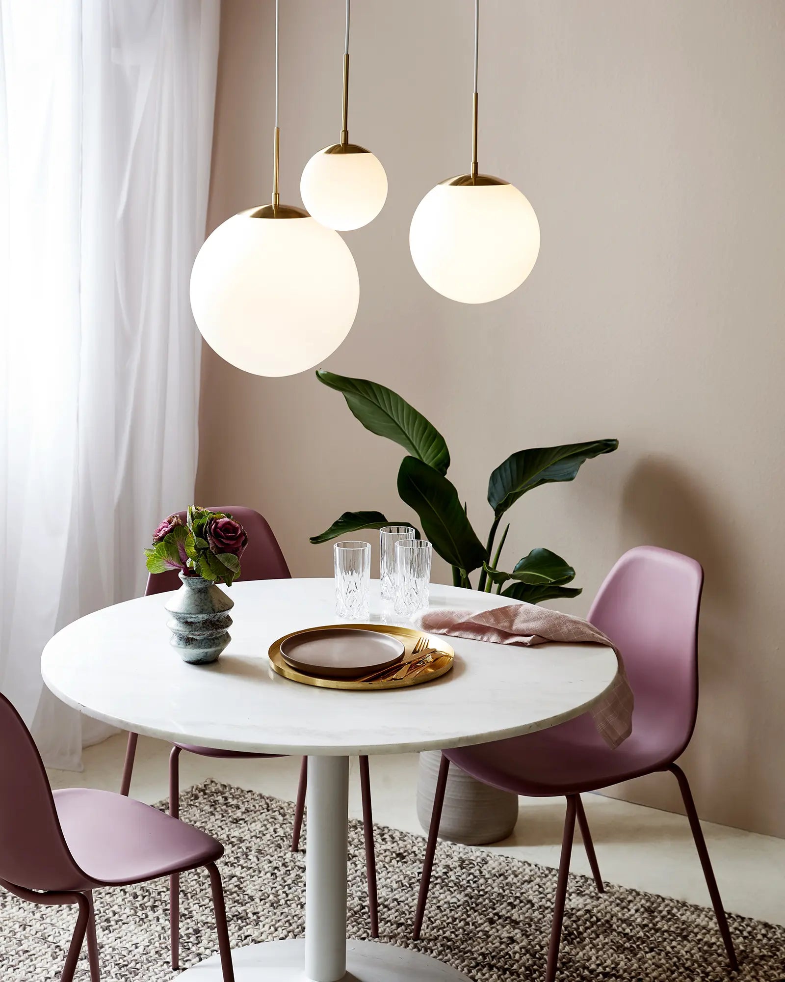 Grant orb pendant light in opal and brass cluster above a dining table