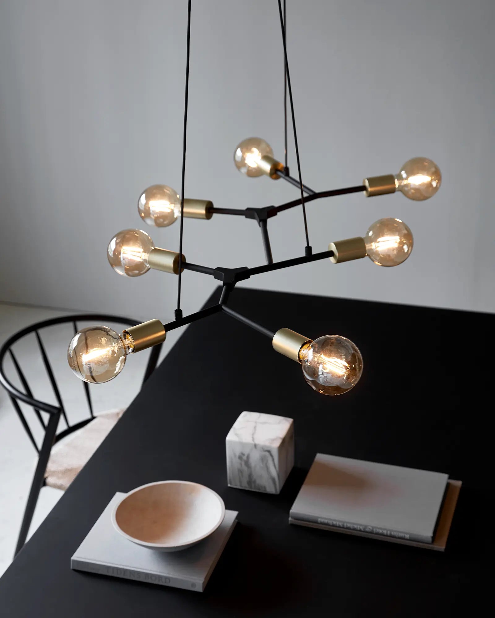 Josefine pendant light in black and brass horizontal above a table