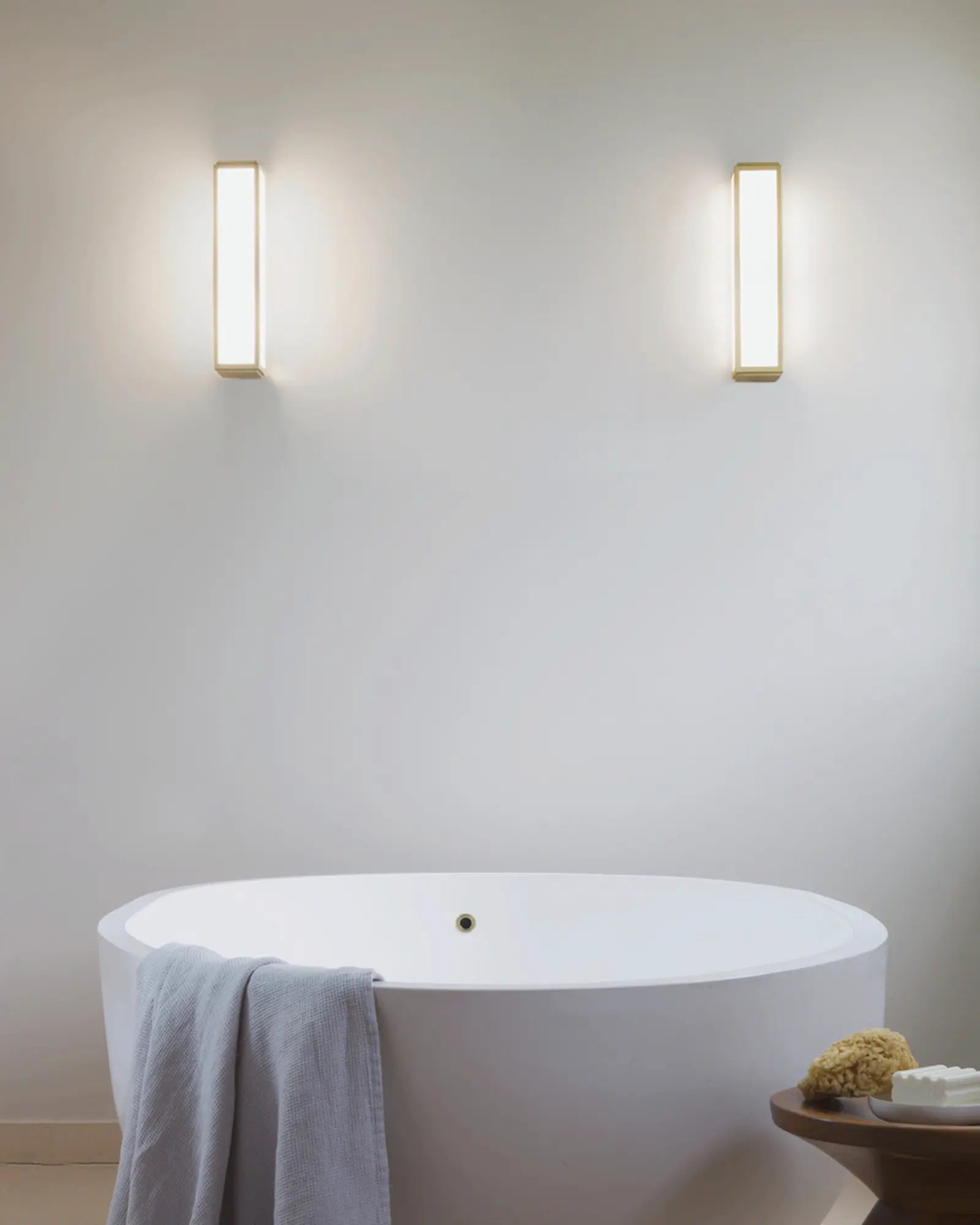 Mashiko metal and glass contemporary bathroom wall light above a bath tub