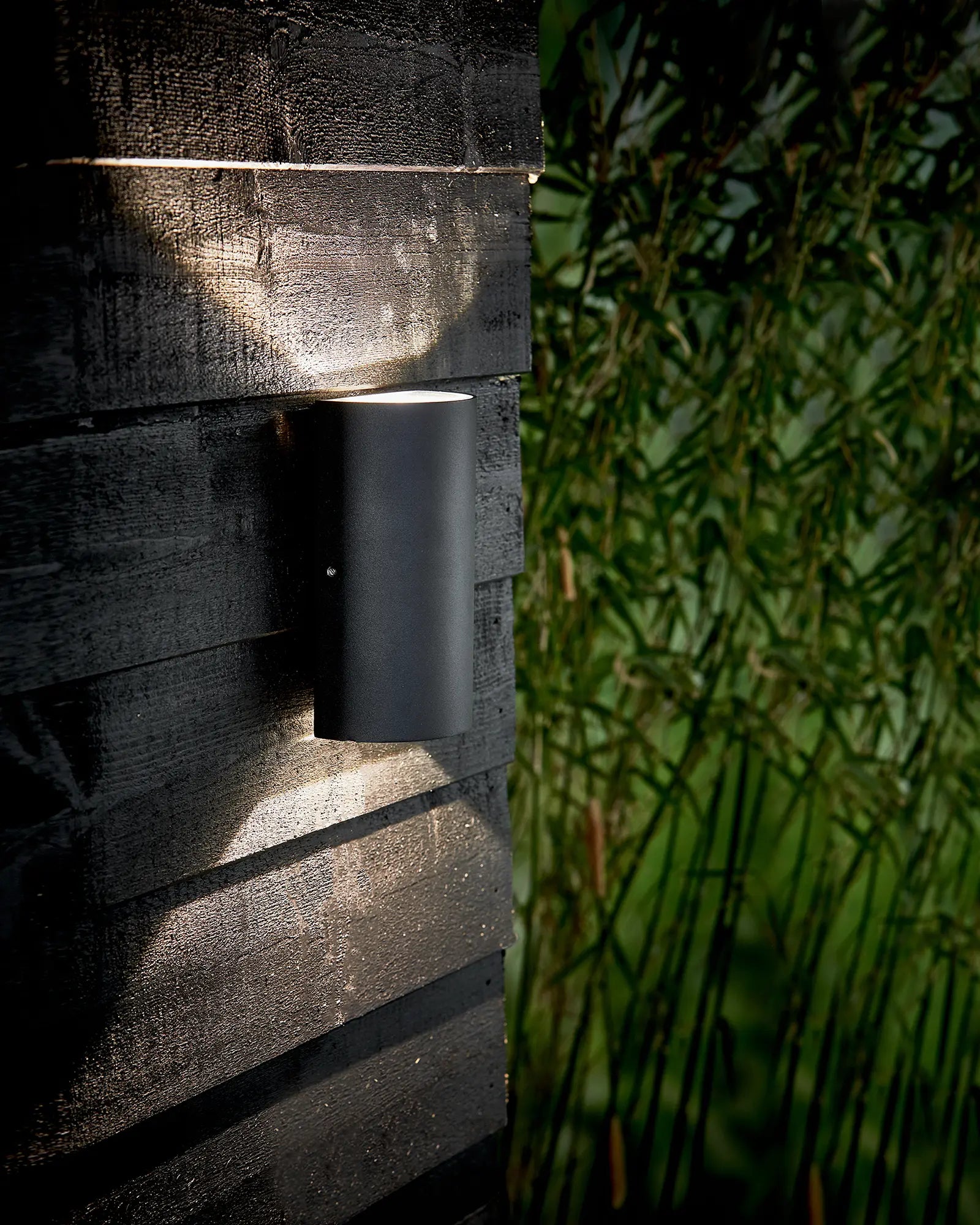 Rold minimal scandinavian half cylinder outdoor wall light in black on cladded timber wall